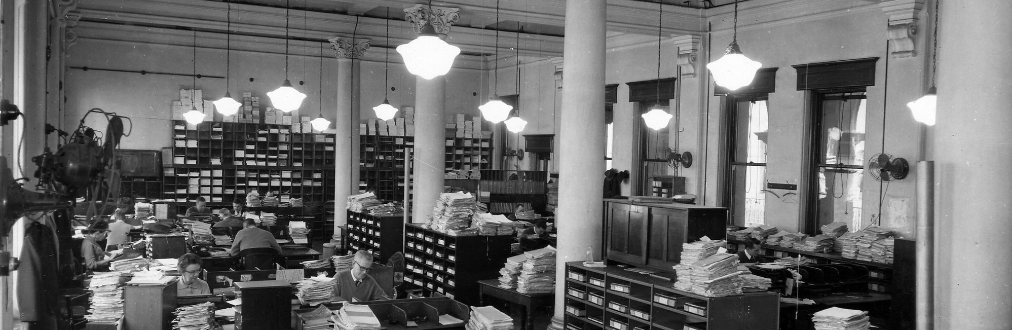A black-and-white mid-century photograph of busy office workers.