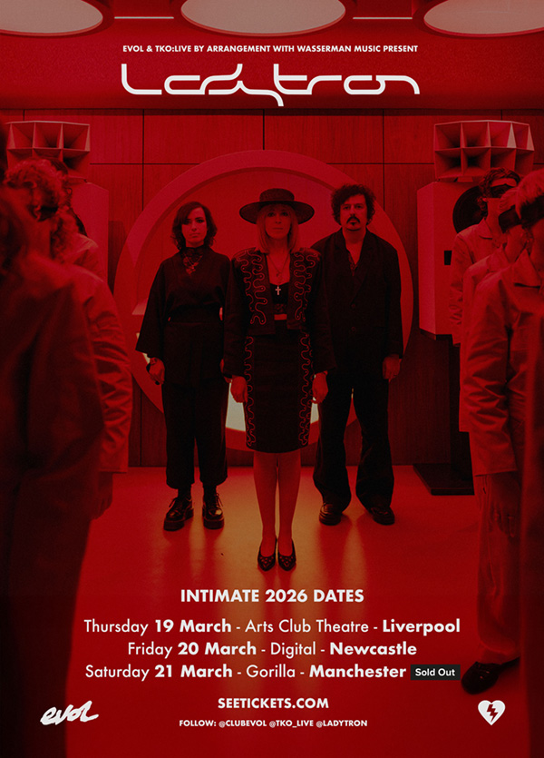 A tour-promotion poster for Ladytron. The three members of Ladytron, dressed quite fashionably in black, standing in a triangular formation amidst columns of blindfolded people dressed in white.