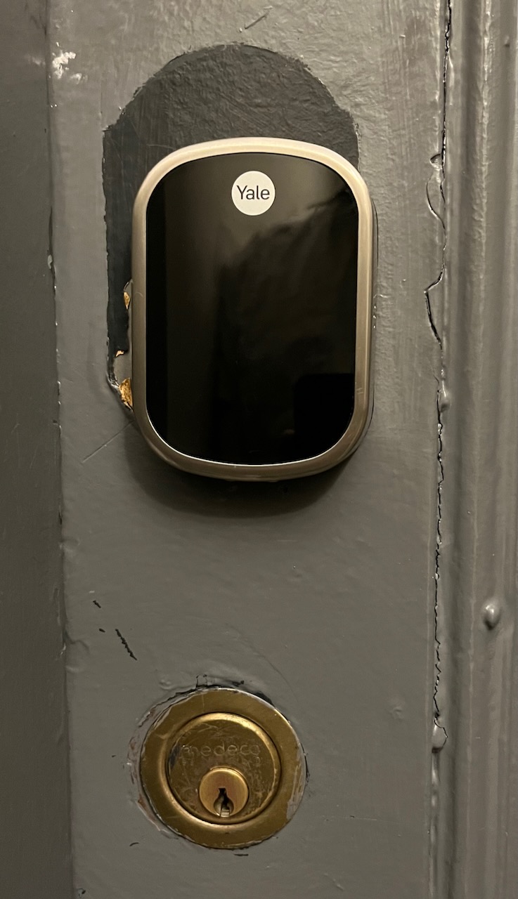 Photo of a shiny new Yale deadbolt keypad installed in a old and somewhat shabby-looking door.